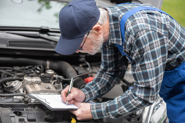 Car mechanic checking a car engine