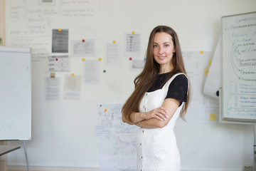 Beautiful young woman looking at camera in classroom against whiteboard