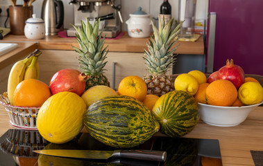 Many varieties of fresh and exotic fruits standing on a cooking island in front of it lies a...