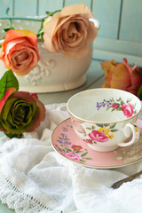 Antique floral cup, saucer and vintage roses, vertical image