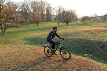 Fototapeta premium Cyclist in shorts and jersey on a modern carbon hardtail bike with an air suspension fork standing on a cliff against the background of fresh green spring forest