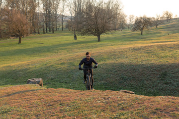 Fototapeta premium Cyclist in shorts and jersey on a modern carbon hardtail bike with an air suspension fork standing on a cliff against the background of fresh green spring forest