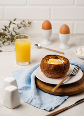 Baked Egg inside a bun. Breakfast with Eggs and Orange Juice.