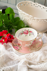 Antique porcelain tea cup on white lace table cover, vertical image