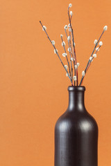 vertical pussy willow sunday (palm sunday) feast still-life - natural pussy-willow twigs in ceramic bottle on brown pastel background with copyspace