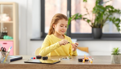 children, technology and science concept - happy girl playing with robotics kit at home