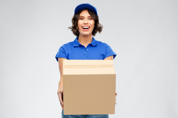 mail service and shipment concept - happy smiling delivery girl with parcel box in blue uniform over grey background