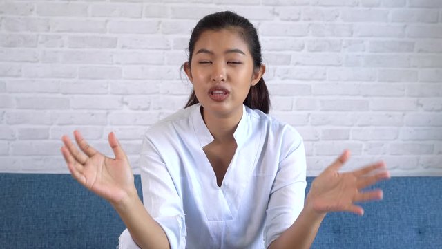 Happy friendly Asian woman looking at camera and talking, making video call conference, online job interview at home. Millennial female internet teacher tutor and vlogger on the job.