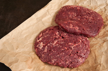 Juicy homemade beef cutlets are close-up ready for cooking on a dark background in the kitchen. Selective focus.