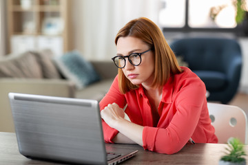 remote job, technology and people concept - bored or tired young woman in glasses with laptop computer working at home office