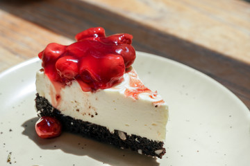 Slice of plain cheesecake with strawberry sauce on white plate.