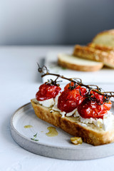 Tomato confit and goat cheese bruschetta on grey concrete table. Selective focus