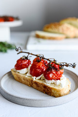 Tomato confit and goat cheese bruschetta on grey concrete table. Selective focus