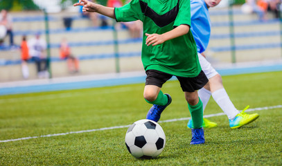 Young boys playing football game. Young players kicking soccer ball on sports grass pitch. Happy...