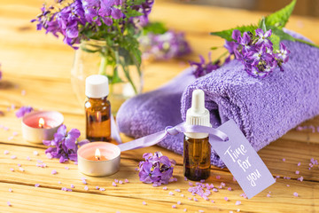 Obraz na płótnie Canvas Time for you text phrase on label sticker. Spa still life with violet oil, towel and perfumed candle on natural wood table surface