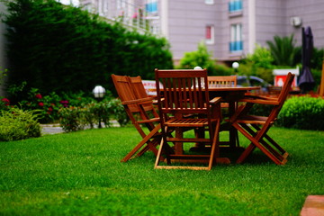 Fototapeta na wymiar wooden garden table and chairs. Wooden dining table and wooden chairs on the grass.