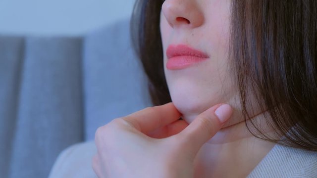 Closeup of woman's secong chin, problems with excess weight. Woman is touching her chin to demostrate her cosmetic problem. Examining double chin, need facial line correction.