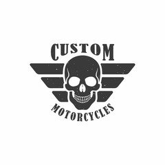 Black and white illustration of a skull, wings and text with texture on a white background. A vector illustration advertises custom motorcycle workshop. Logo biker club.