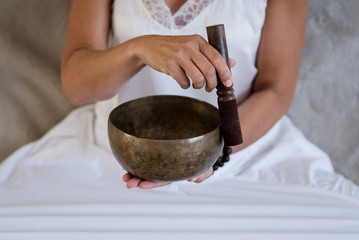 Woman doing yoga with tibetian singing bowl at home