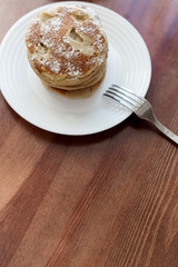 pancakes with berries and powdered sugar in a white plate are on the table