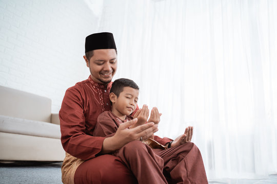 Muslim father and son praying together at home