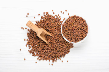 brown buckwheat grains in wooden bowl on isolated white background Healthy food, superfood concept
