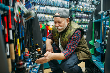 Fisherman choosing reel in fishing shop