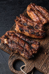 Closeup of pork ribs grilled on cutting board on dark concrete background