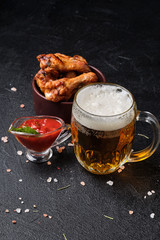 Glass of beer, grilled chicken wings and tomato sauce