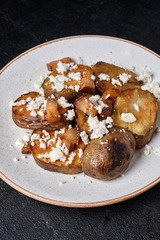 Slices of baked potatoes with feta cheese and bacon on a white plate