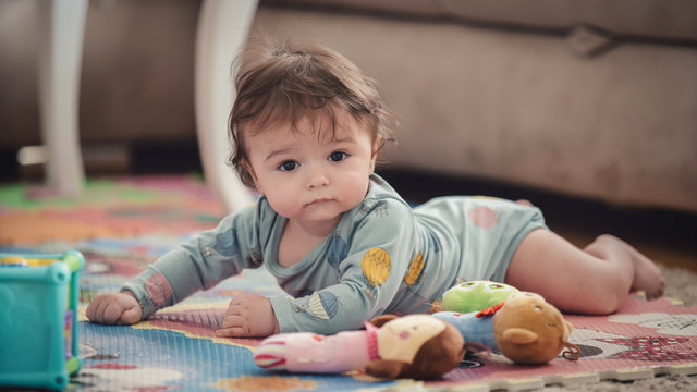 A cute young baby playing inside home with colorful toys
