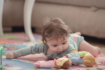 A cute young baby playing inside home with colorful toys