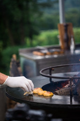 Hand in a glove cooking vegetables on a grill. Swapping potatoes