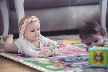 Fototapeta na wymiar cute twins, baby girl and baby boy playing with toys by the home