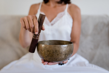 Woman doing yoga with tibetian singing bowl at home