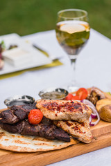 Beef steak on a plate with butter on it, corn and cherry tomatoes and white sous.
