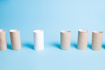 hubs from toilet paper stand in a row, social distance concept, blue background, copy space, one sleeve is white and stands at a distance