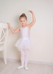 Cute little girl dreams of becoming a ballerina. Child girl in a white  tutu tying her ballet slippers. Baby girl studying practicing ballet. © Polina Ponomareva