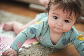Fototapeta premium A cute young baby playing inside home with colorful toys