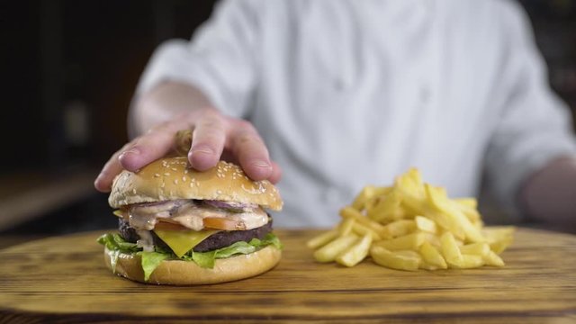 shef povar gotovit na kukhne na otkrytom ogne gotovit burger, vykladyvayet ovoshi na burger, prigotovleniye burgera na kukhne
the chef cooks in the kitchen on an open fire preparing a burger, puts ve
