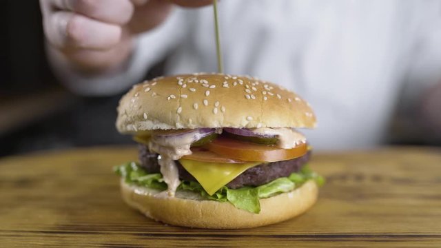 shef povar gotovit na kukhne na otkrytom ogne gotovit burger, vykladyvayet ovoshi na burger, prigotovleniye burgera na kukhne
the chef cooks in the kitchen on an open fire preparing a burger, puts ve