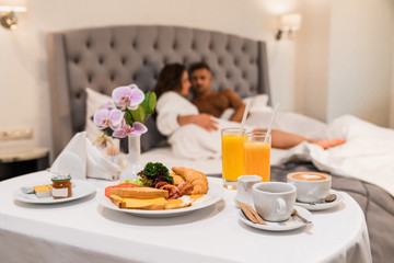 Eggs and coffee room service in hotel concept, blurred couple on a background