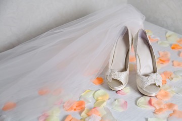 Shoes of the bride, decorated with embroidery with a veil, a veil. Romantic morning of the bride, rose petals on the table