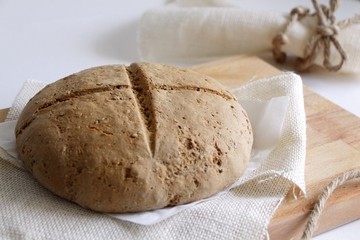 Whole-wheat bread on wooden cutting board closeup. Concept of fresh pastry, healthy homemade food.