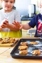 Kids making cookies in kitchen placing dough on tray for cooking at home