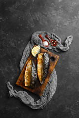 Delicious baked mackerel fillet with paprika, garlic and lemon, on a dark wooden Board with spices in the background. Top view, side view, close-up. Space for text.