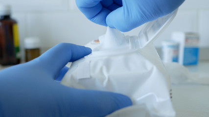 Fototapeta premium Social Distancing Lifestyle, Hands Protected with Gloves Taking Wet Wipes from a Package Used for Cleanliness