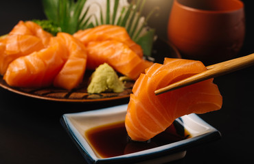 Sashimi, Salmon, Japanese food chopsticks and wasabi on the wood table
