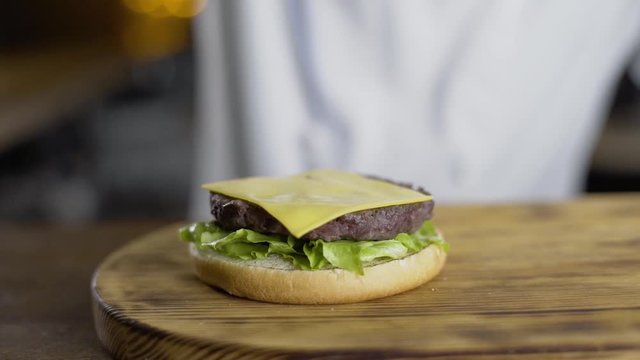 shef povar gotovit na kukhne na otkrytom ogne gotovit burger, vykladyvayet ovoshi na burger, prigotovleniye burgera na kukhne
the chef cooks in the kitchen on an open fire preparing a burger, puts ve