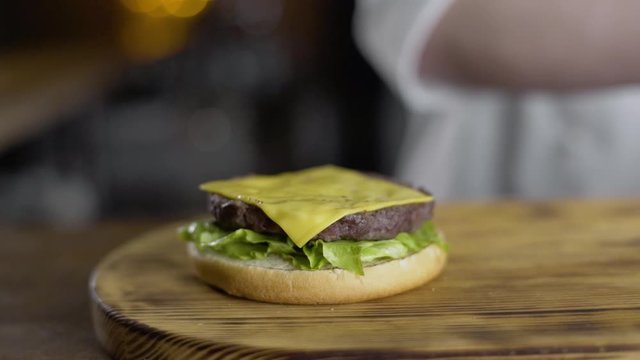 shef povar gotovit na kukhne na otkrytom ogne gotovit burger, vykladyvayet ovoshi na burger, prigotovleniye burgera na kukhne
the chef cooks in the kitchen on an open fire preparing a burger, puts ve